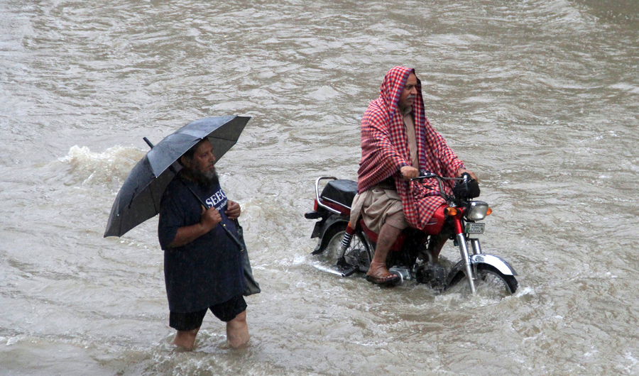 A man holds an umbrella as he walks through floodwaters during heavy rain in Lahore, Pakistan, on July 3, 2018. (REUTERS)