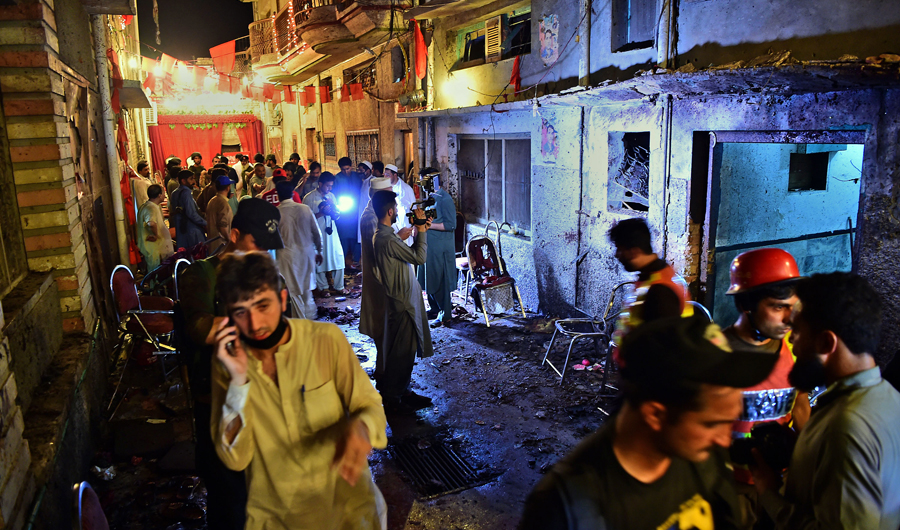 Pakistani security officials and volunteers search the site after a suicide bombing at an election rally in Peshawar on July 10, 2018. (AFP)