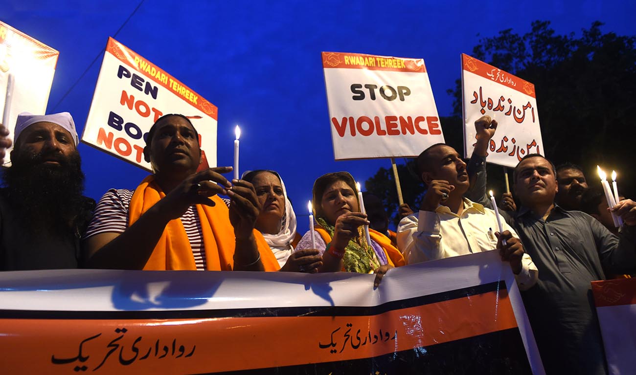 In this file photo, Pakistani Christians hold candles and placards during a vigil for the overnight blast victims in Lahore on July 11, 2018. (ARIF ALI/AFP)