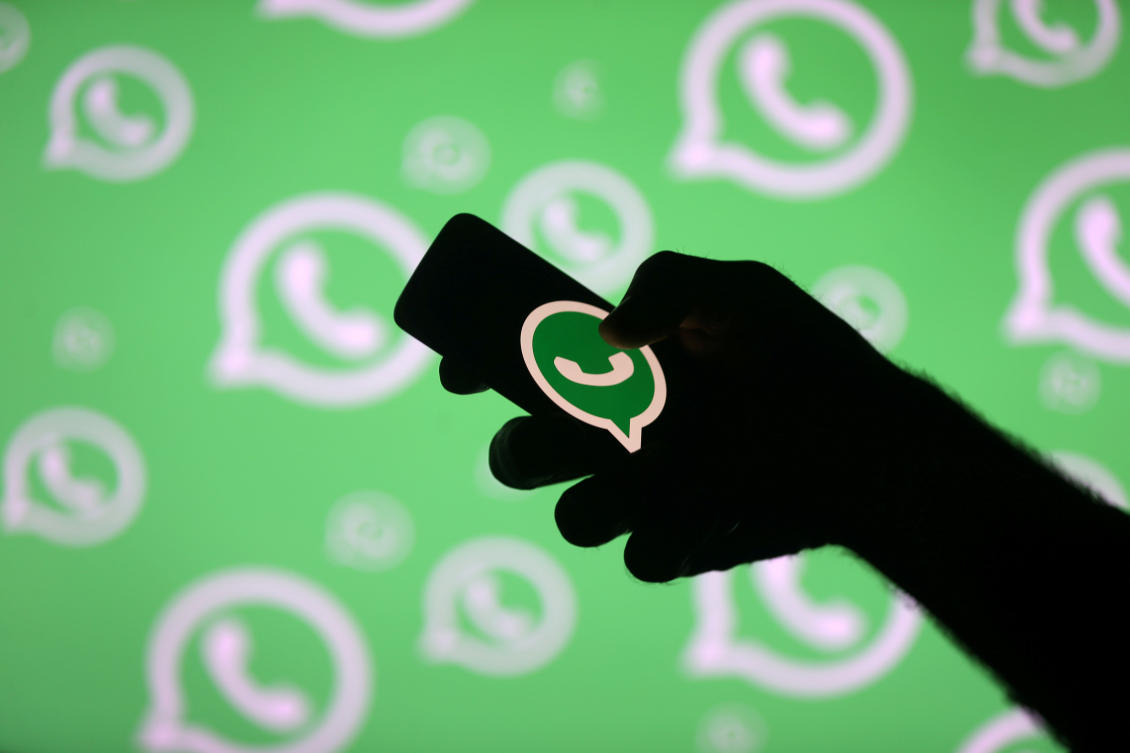A man poses with a smartphone in front of displayed Whatsapp logo in this illustration September 14, 2017. (Reuters)