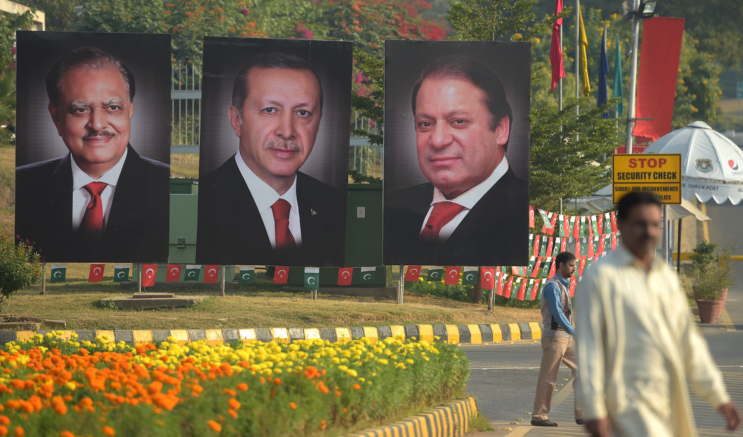 In this file photo, Pakistani men walk past billboards showing the portraits of Turkish President Recep Tayip Erdogan, center, Pakistani President Mamnoon Hussain, left, and Prime Minister Nawaz Sharif in Islamabad on Nov. 17, 2016. President Erdogan sends good wishes to Sharif family for upcoming elections. (AAMIR QURESHI/AFP)