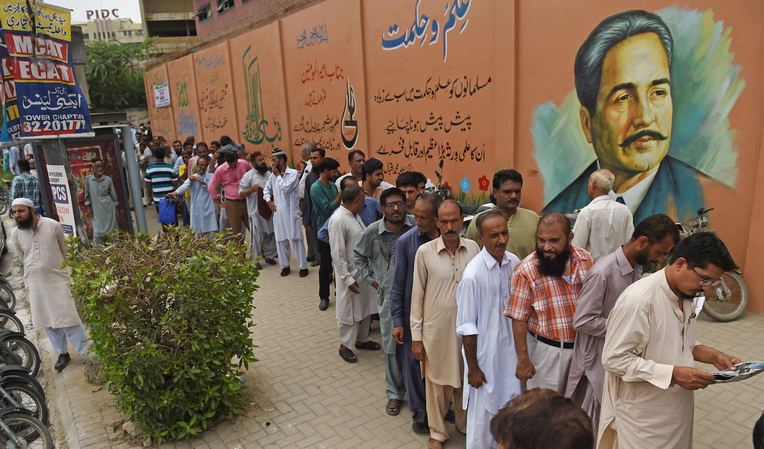 Pakistani election officials wait outside a distribution centre to collect ballot boxes and voting materials in Karachi on July 24, 2018. Pakistan will hold its general election on July 25. (RIZWAN TABASSUM/AFP)