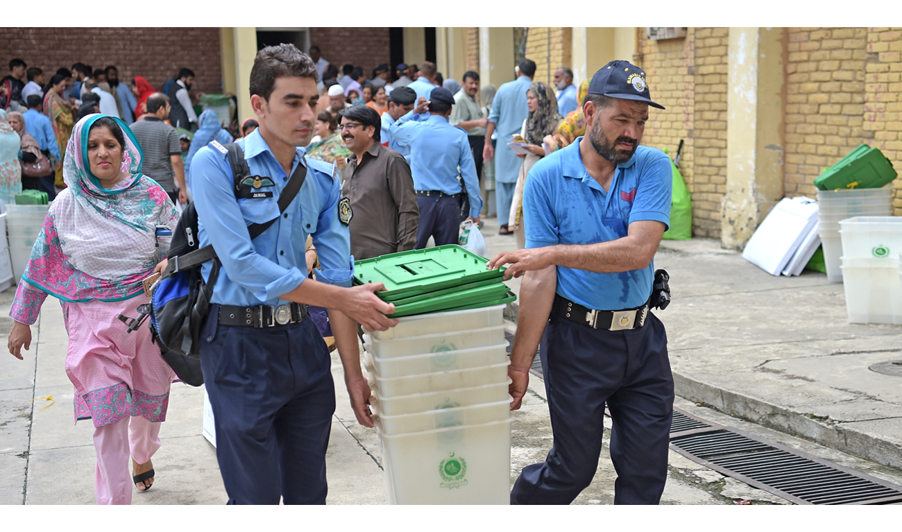 Pakistani policemen help election officials to carry ballot boxes at a distribution centre in Islamabad on July 24, 2018. (AAMIR QURESHI/AFP)