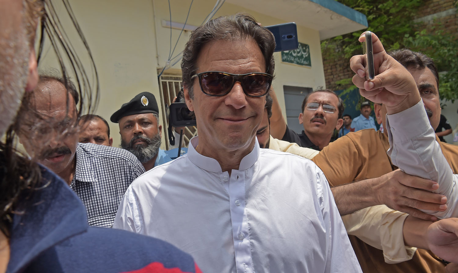 Pakistan’s cricketer-turned politician Imran Khan, center, head of the Pakistan Tehreek-e-Insaf (Movement for Justice) party, arrives to cast his vote during the general election in Islamabad on July 25, 2018. (AAMIR QURESHI/AFP)