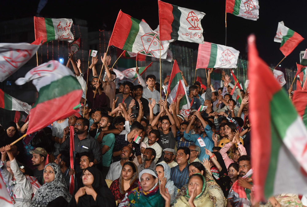 Supporters of Pakistani political Muttahida Qaumi Movement (MQM) party hold party flags as they attend a campaign meeting ahead of the general election in Karachi on July 23, 2018. (AFP / ASIF HASSAN)