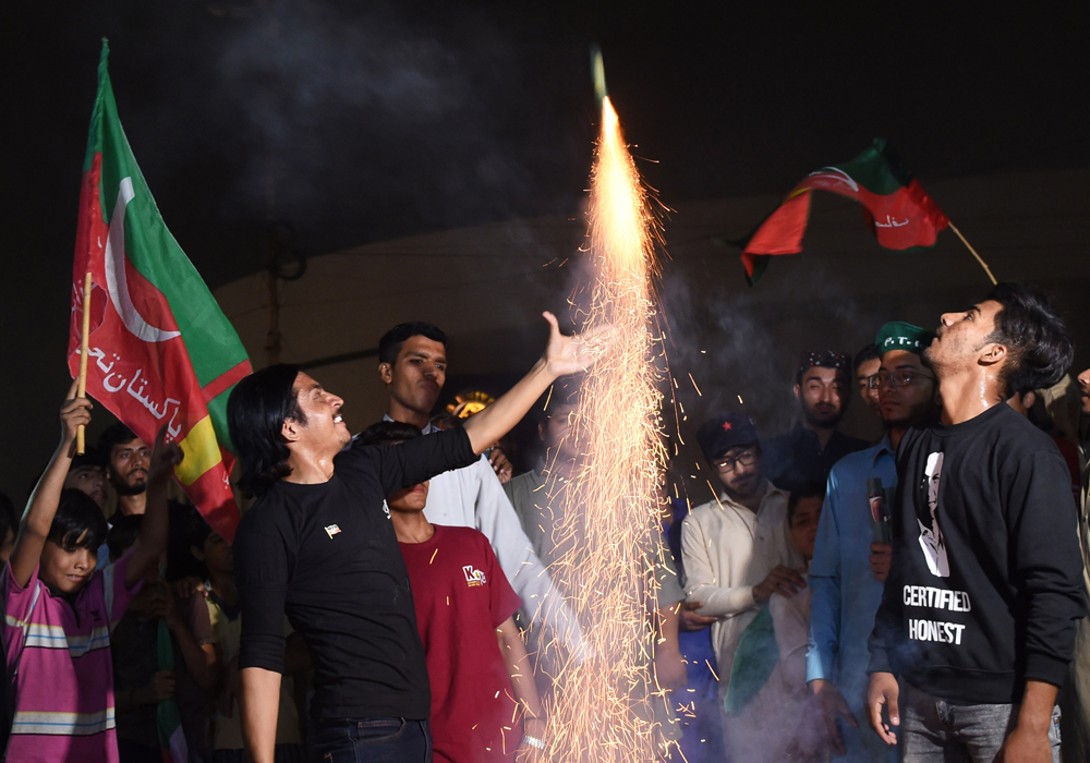 Supporters of Pakistan's cricketer-turned politician Imran Khan, and head of the Pakistan Tehreek-e-Insaf (Movement for Justice) party, celebrate in Karachi on July 27, 2018. A group of Pakistani political parties announced on July 27, a protest demanding new elections following allegations of rigging in this week's nationwide polls that were won by cricket hero Imran Khan's party. (AFP / RIZWAN TABASSUM)