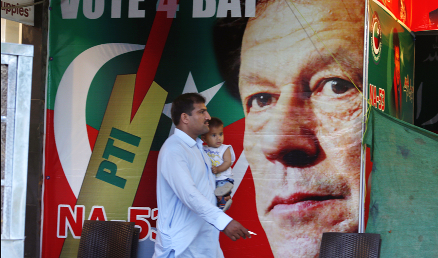 A Pakistani walks past a poster of Imran Khan, head of Pakistan Tehreek-e-Insaf party, at a market in Islamabad, Pakistan, on July 28, 2018. The party of cricket star Imran Khan says it has acquired the support of the lawmakers required to form a coalition government after winning this week's polls. (AP)