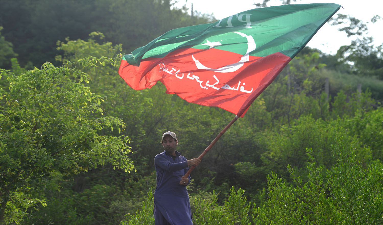A supporter of Pakistan’s cricketer-turned politician Imran Khan, and head of the Pakistan Tehreek-e-Insaf (Movement for Justice) party, waves a party flag near his residence in Islamabad on July 26, 2018, a day after the general election. (AAMIR QURESHI/AFP)