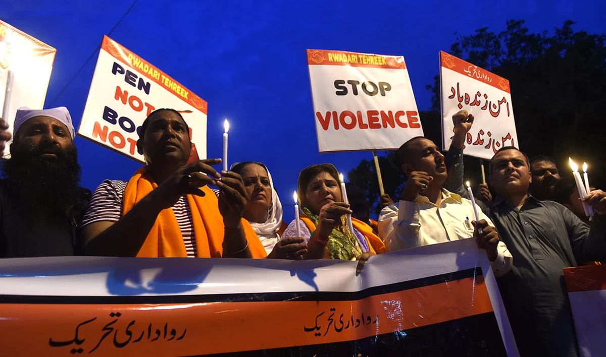 In this file photo, Pakistani Christians hold candles and placards during a vigil for the overnight blast victims in Lahore on July 11, 2018. (ARIF ALI/AFP)