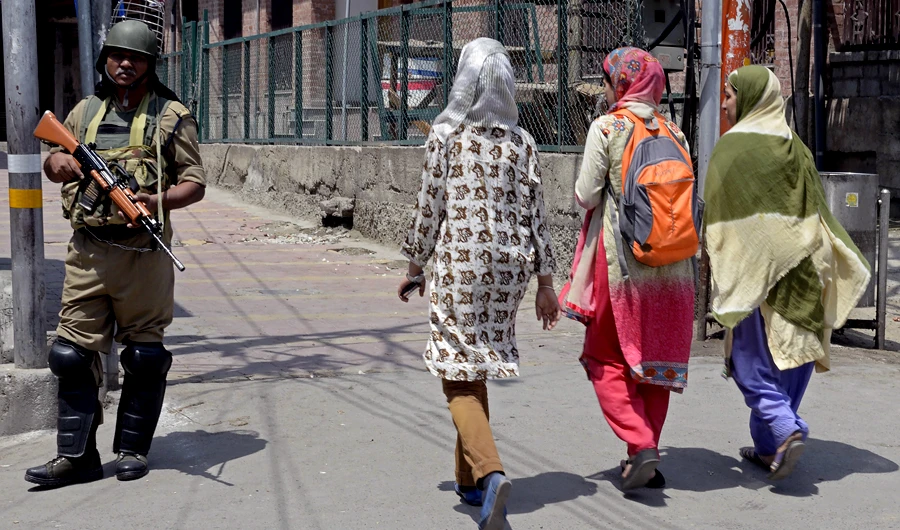 In this file photo taken on July 07, 2018, Indian paramilitary trooper stands guard as Kashmiri girls walk past during a one-day strike in Srinagar. (AFP)