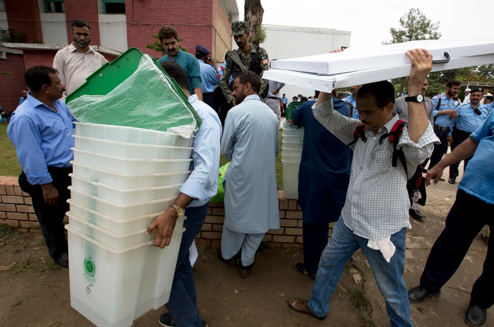 Pakistani election staff carry polling material to stations at a distribution center in Islamabad, Pakistan, on the eve of Pakistan national election on Wednesday. (AP Photo/B.K. Bangash)