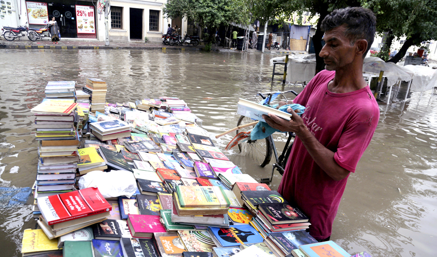 A vendor cleans old books at his stall on a flooded street following heavy rain in Lahore, Pakistan, on July 22, 2018. Flash floods are common across Pakistan during the monsoon rains. (AP)