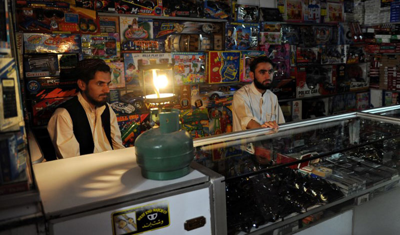 Pakistani shopkeepers wait for customers in a shop during a power outage. (AFP)