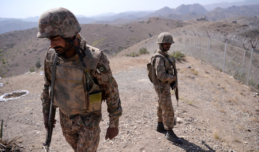 In this file photo, Pakistani soldiers patrol next to a newly fenced border separating North Waziristan and Afghanistan. A roadside bomb has killed a soldier and wounded another three in the northwest along the Afghan border. (AFP/photo)