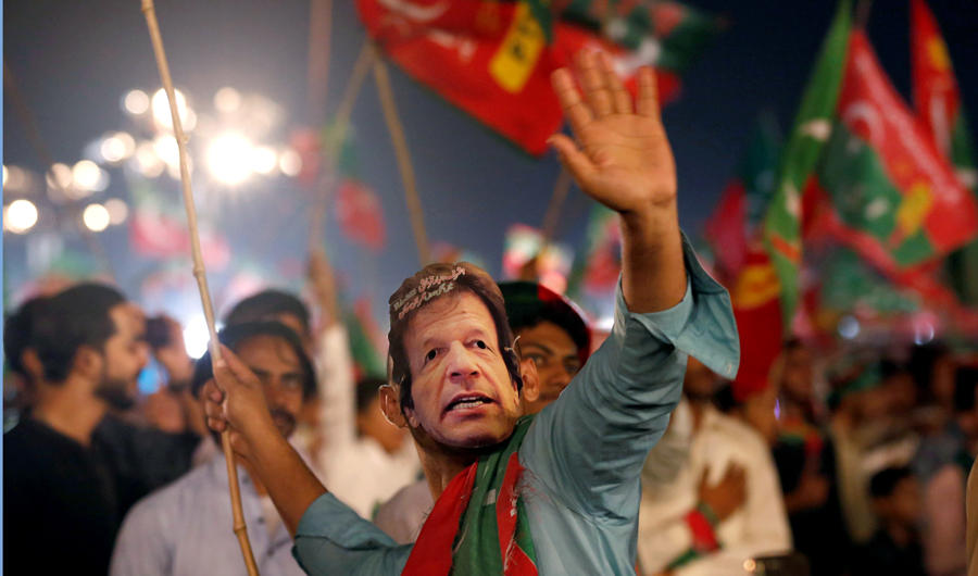 A supporter of Imran Khan, chairman of the Pakistan Tehreek-e-Insaf (PTI), political party, wears a mask and dance on party songs during a campaign rally ahead in Karachi last month. An anthem prepared by Khan's party is being criticized S being copied from India. (REUTERS/Akhtar Soomro/File Photo)