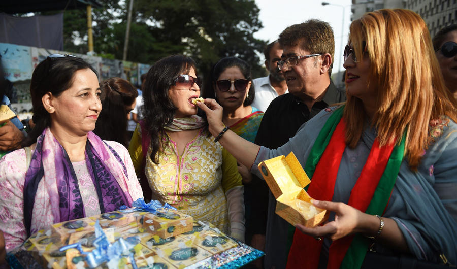 Supporters of Pakistan's cricketer-turned politician and head of the Pakistan Tehreek-e-Insaf (Movement for Justice) Imran Khan, distributes sweets in Karachi after Khan take oath as a Prime Minister on August 18, 2018. Despite the strong support of women for Khan, the number of women appointed to key positions in Khan's government is minimal. (AFP / RIZWAN TABASSUM