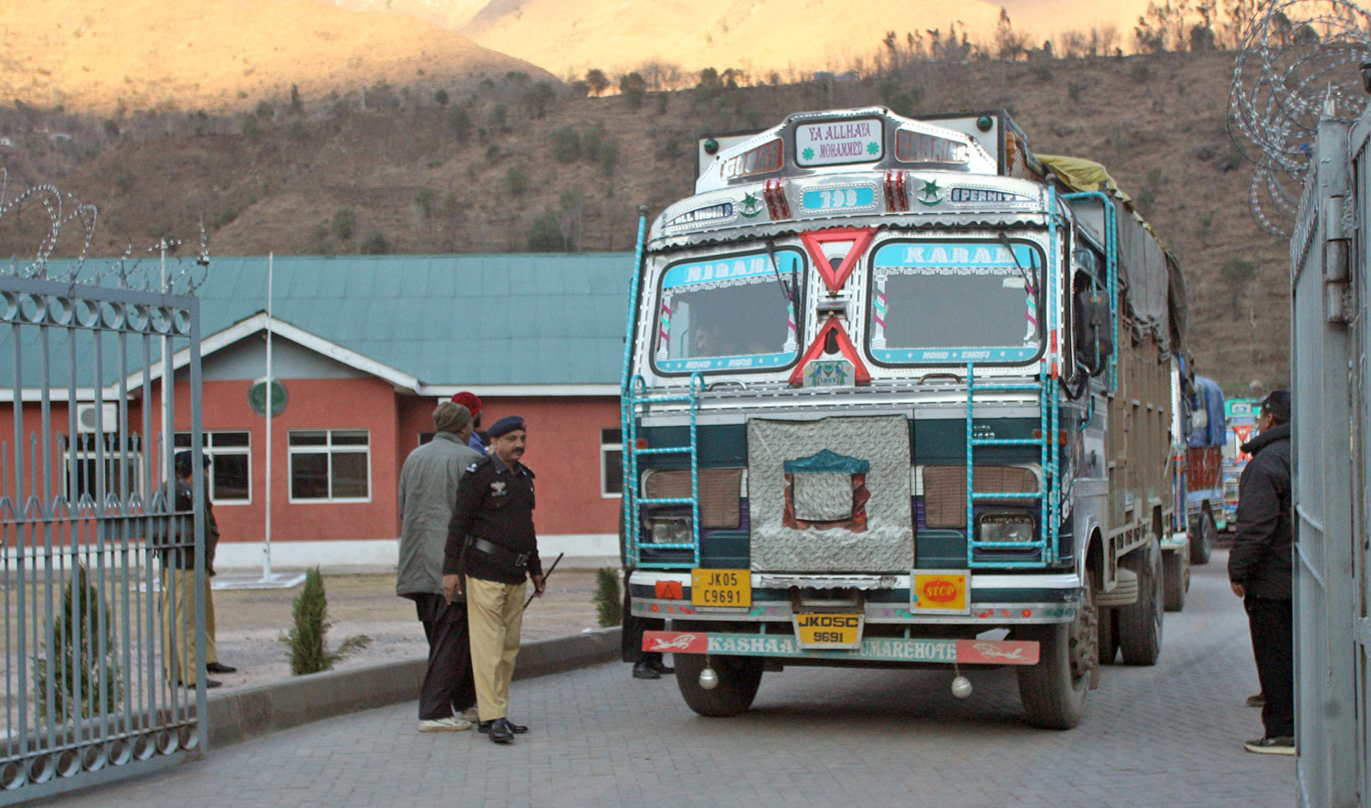In this file photo, Pakistani policemen make way for Indian trucks as they leave the Trade Facilitation Centre before crossing the border in Chakoti, just inside Pakistan-administered Kashmir, Feb. 12, 2014. (AFP)