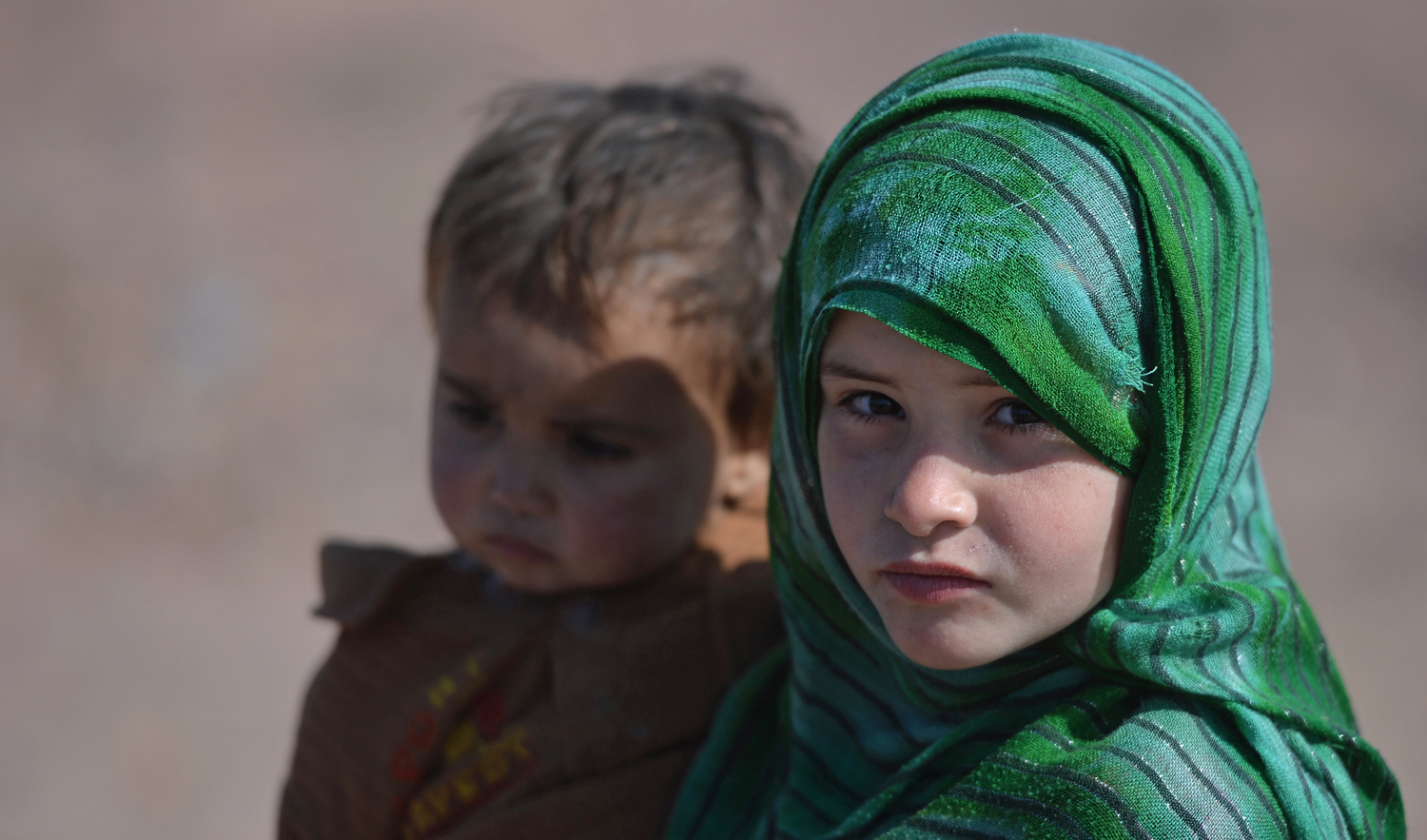 In this file photo, an Afghan refugee girl carries her brother at a refugee camp on the outskirts of Islamabad on Feb. 1, 2018. (AFP)