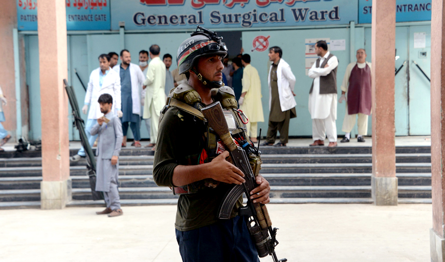 An Afghan policeman stands as unseen volunteers carry an injured on a stretcher to a hospital, following an attack that targeted a parliamentary election rally in the Kama district of the eastern province of Nangarhar, in Jalalabad on Oct. 2, 2018. (AFP)