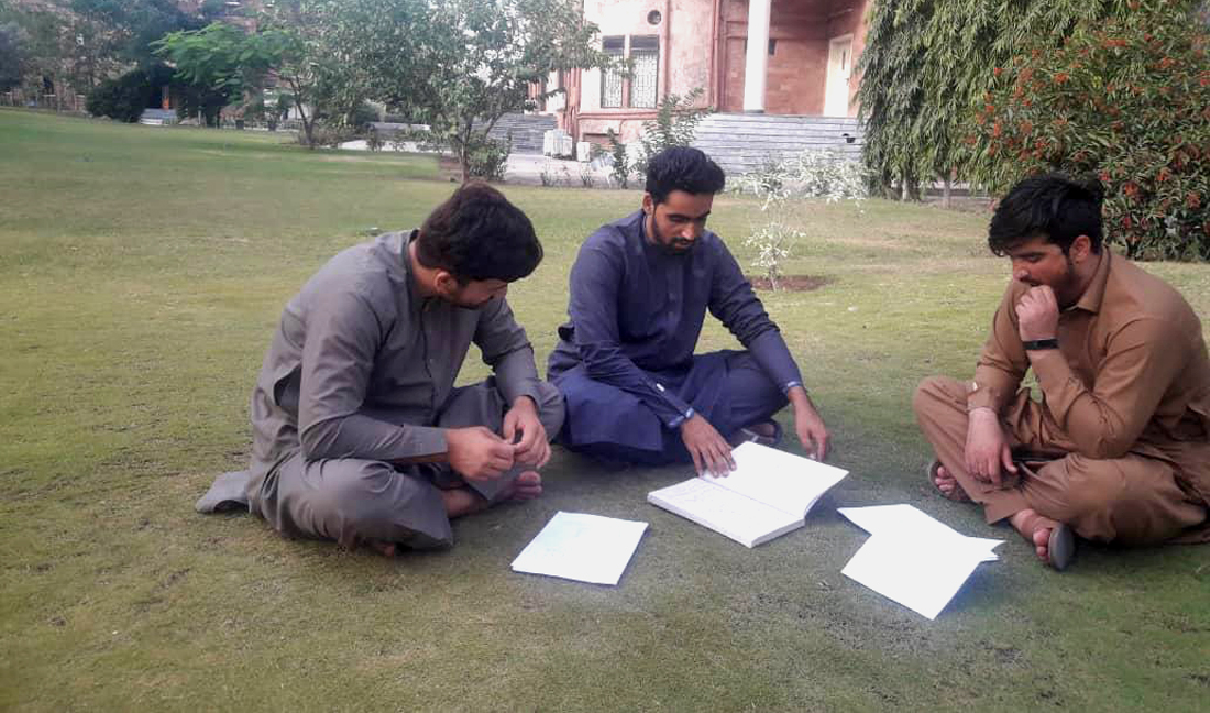 Rohul Amin, center, studies with his colleagues at the lawn of Institute of Management Sciences in Peshawar. (AN photo)