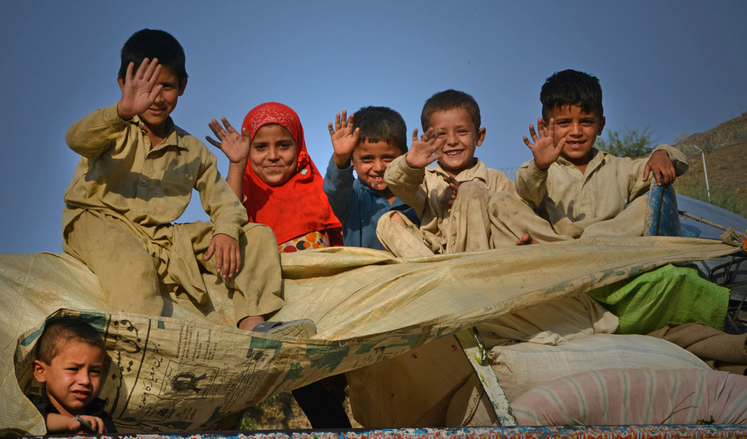 In this file photo, repatriated Afghan refugee children wave as they travel in a packed vehicle preparing to cross the border into Afghanistan, at the Torkham crossing point in Pakistan’s tribal Khyber district on Sept. 7, 2016. (AFP)