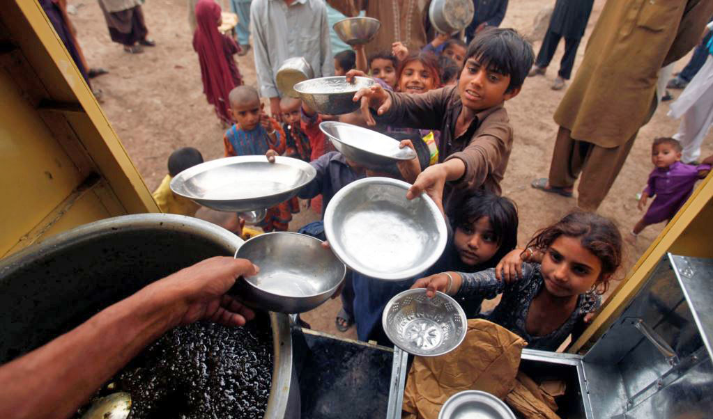 In this file photo, children hold their bowls as they wait in line for a charity food handout in Peshawar, Pakistan March 13, 2018. (REUTERS)