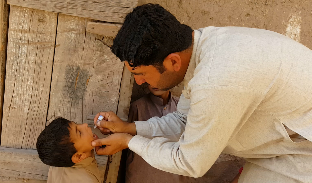 A polio worker administers anti-polio drops to a child in tribal district. (Photo courtesy: KP Emergency Operation Center)
