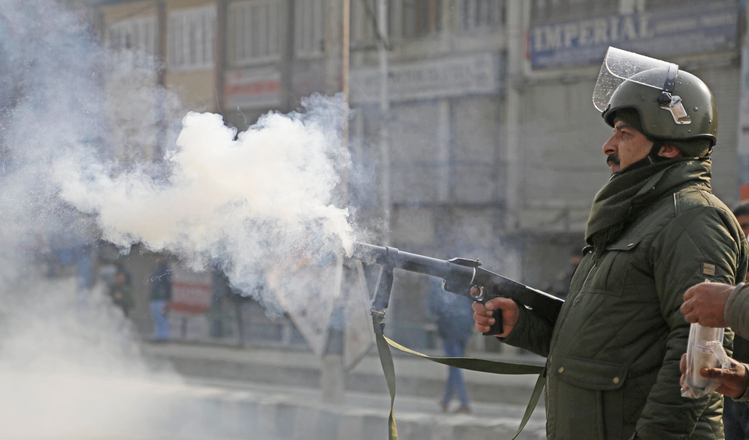 An Indian police officer fires tear smoke shell on Kashmiri protesters attempting to march to an Indian military base in Srinagar, Monday, Dec. 17, 2018. (AFP)