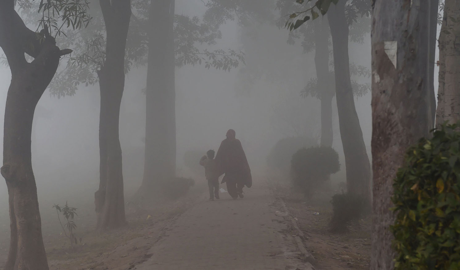 A Pakistani woman and her child during dense fog and smog in Lahore on Dec. 24, 2018. (AFP)
