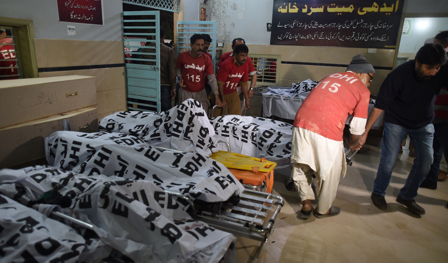 Pakistani volunteers handle the burnt remains of bus passengers at an Edhi Foundation mortuary in Karachi on January 22, 2019, following a transport accident. (AFP)
