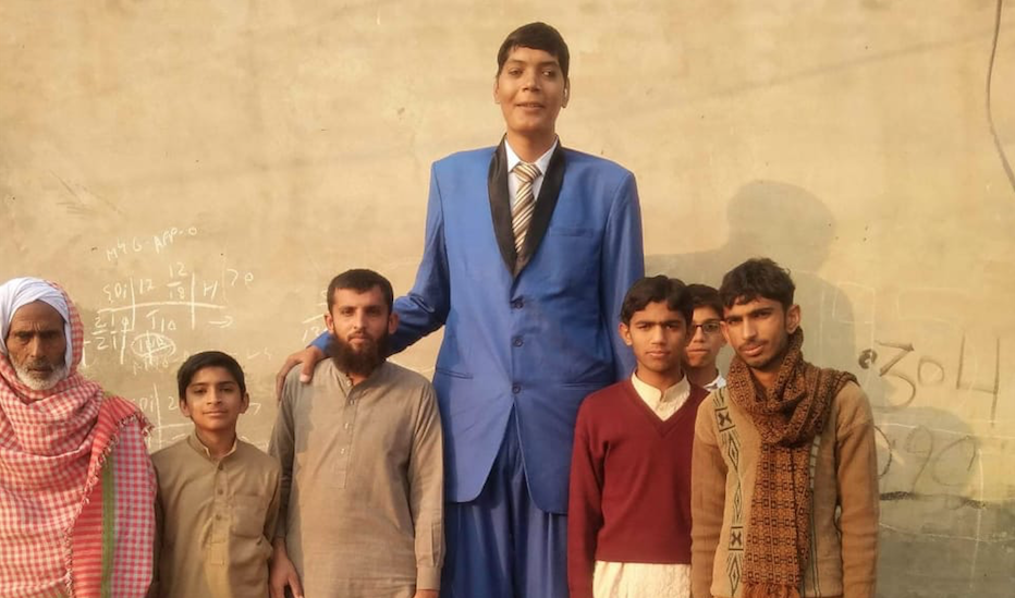Pakistan’s tallest man, Zia Rasheed, outside him home with the kids in Garha More, Punjab. (AN photo)