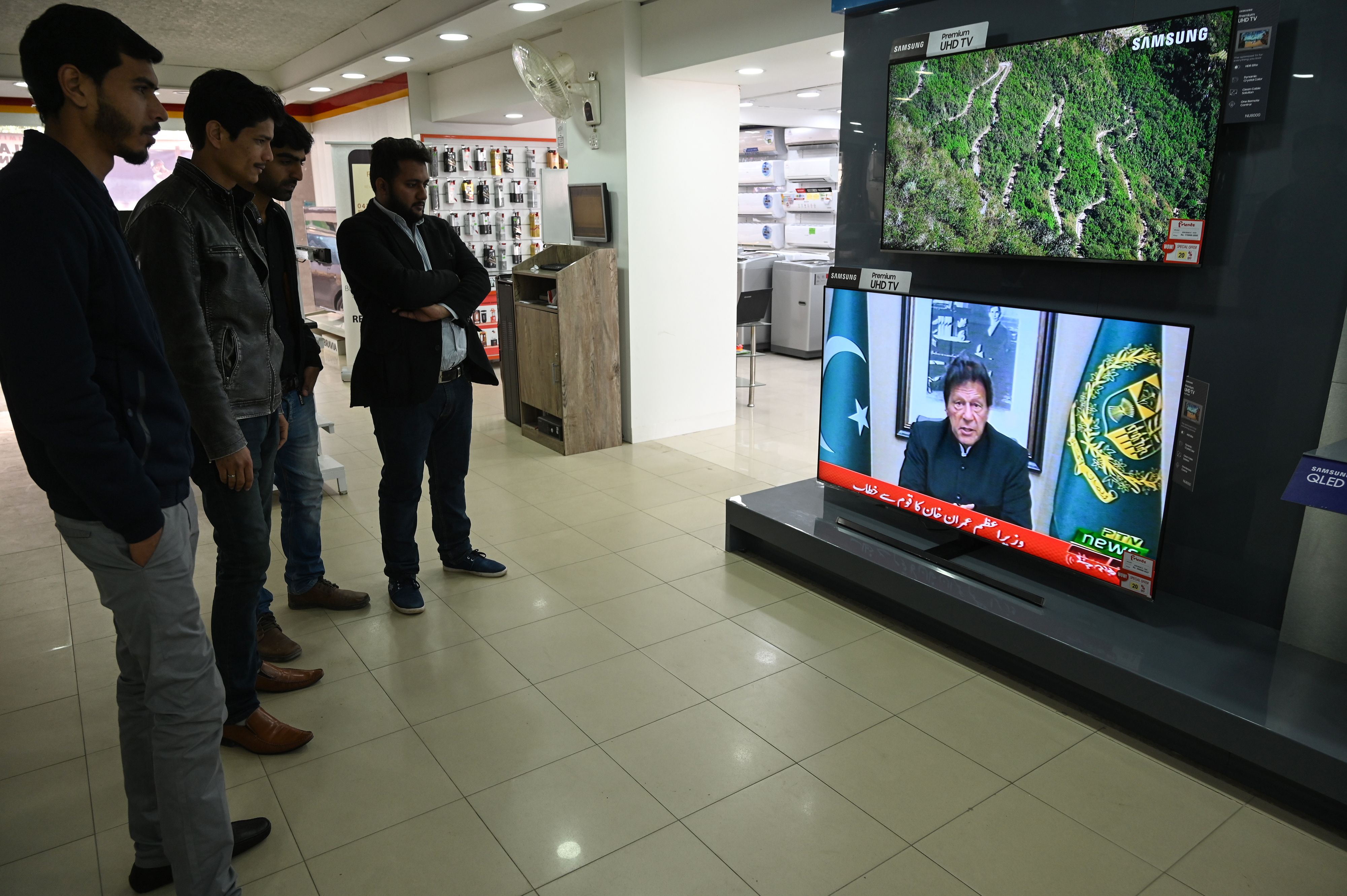 Pakistani people watch the television as Prime Minister Imran Khan addresses the nation on a suicide attack in Indian held Kashmir, in Islamabad on February 19, 2019. Pakistan is ready to help India investigate the deadliest attack in Kashmir in decades, but will retaliate if Delhi attacks, Prime Minister Imran Khan said on February 19 as tensions between the nuclear-armed rivals soared. (AFP)