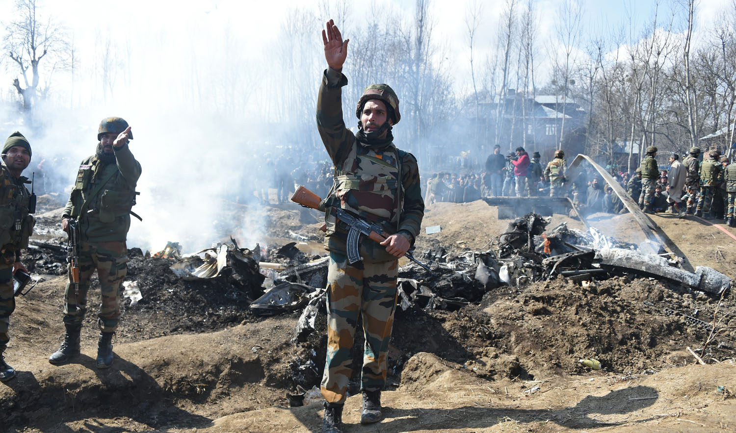 Indian soldiers gesture near the remains of an Indian Air Force aircraft after it crashed in Budgam district, some 30 km from Srinagar on Feb. 27, 2019. (AFP)