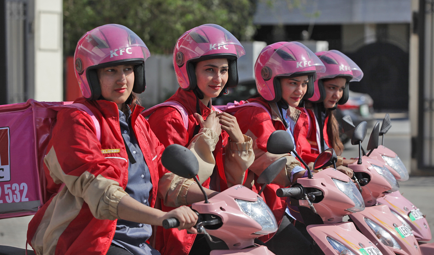 Bisma Mujahid (L), Asma Rani, Beenish Maria and Sadia Eida, Pakistan’s first all-women food delivery crew, pose with their tea-pink scooters outside KFC in Lahore on March 6, 2019. (AN photo by Mohsin Raza)