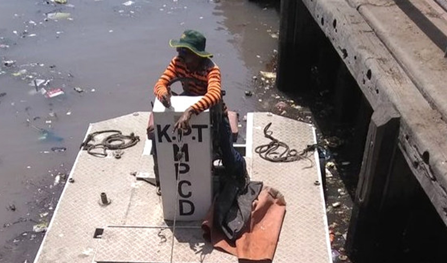 Staff of Karachi Port Trust is cleaning the floating waste thrown by visitors at Kiamari Jetty. (Photo by Ali Haider Zaidi)