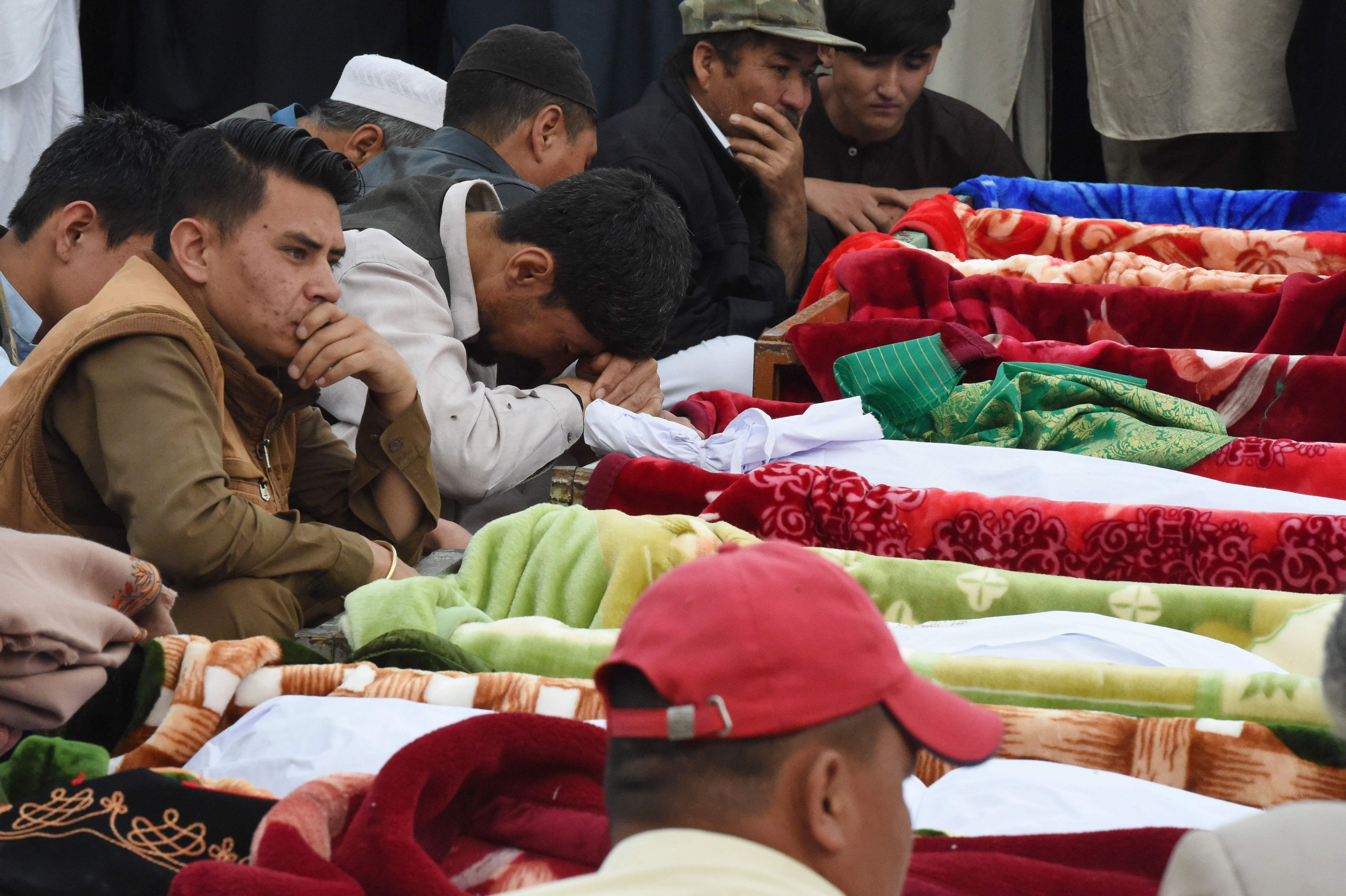 Pakistani mourners of the Shia Hazara ethnic minority sit next the bodies of blast victims during their funeral in Quetta on April 12, 2019, following an attack at a crowded fruit market. (AFP)