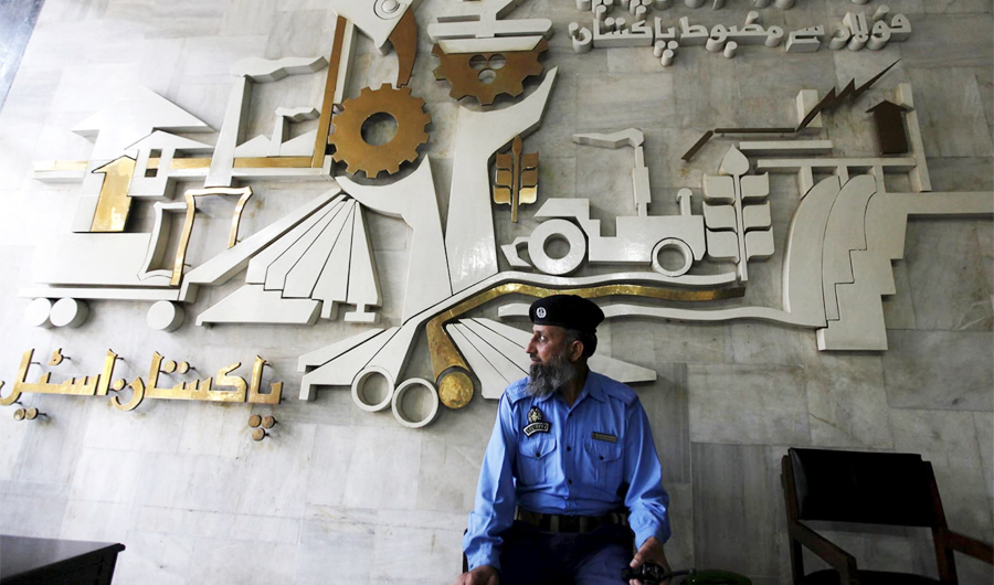 In this Feb 8, 2016 file photo, a security guard sits in front of a wall with signs and slogans at the operation building at the Pakistan Steel Mills (PSM) on the outskirts of Karachi. The Pakistan Stock Exchange (PSX) plunged a massive 816 points on Monday May 13,2019 due to concerns of tough conditions attached with the IMF bailout package. (Reuters/File)