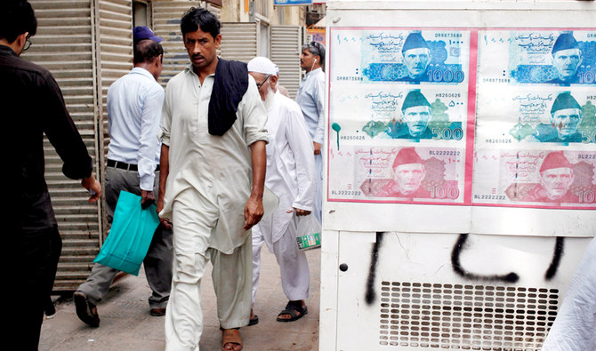 In this file photo, Passersby walk past an advertisement board with photos of Pakistani rupee at a money exchange along a sidewalk in Karachi, Pakistan on June 11, 2018. (REUTERS)