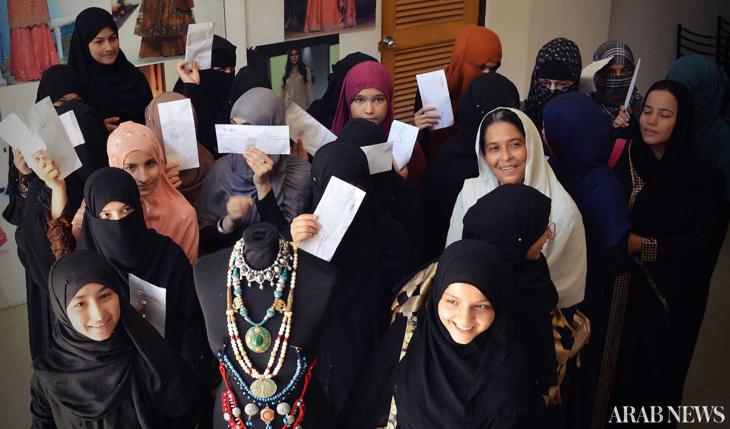 Afghan women from Karachi’s refugee camps hold envelopes containing their first paychecks at FNKAsia’s office in the Korangi neighborhood of Karachi on Sunday. (AN photo)