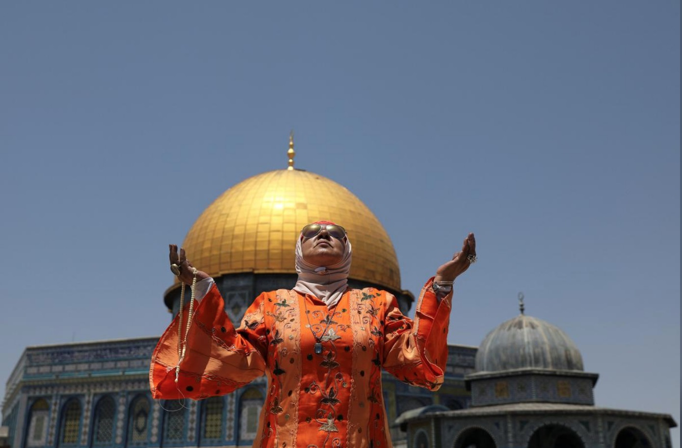 A Palestinian woman prays on the last Friday of Ramadan in front of the Dome of the Rock mosque in Jerusalem, May 31, 2019. (REUTERS)