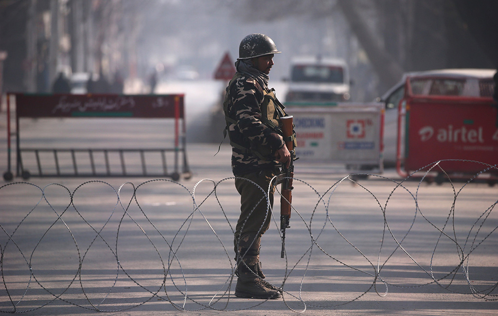 In this December 17, 2018 file photo, an Indian policeman stands guard behind concertina wire laid across a road leading to the Indian army headquarters in Srinagar. The Organization of Islamic Cooperation appointed special envoy for Jammu and Kashmir on Saturday to help resolve the decades-old conflict between South Asia’s two nuclear-armed powers, India and Pakistan. (Reuters)