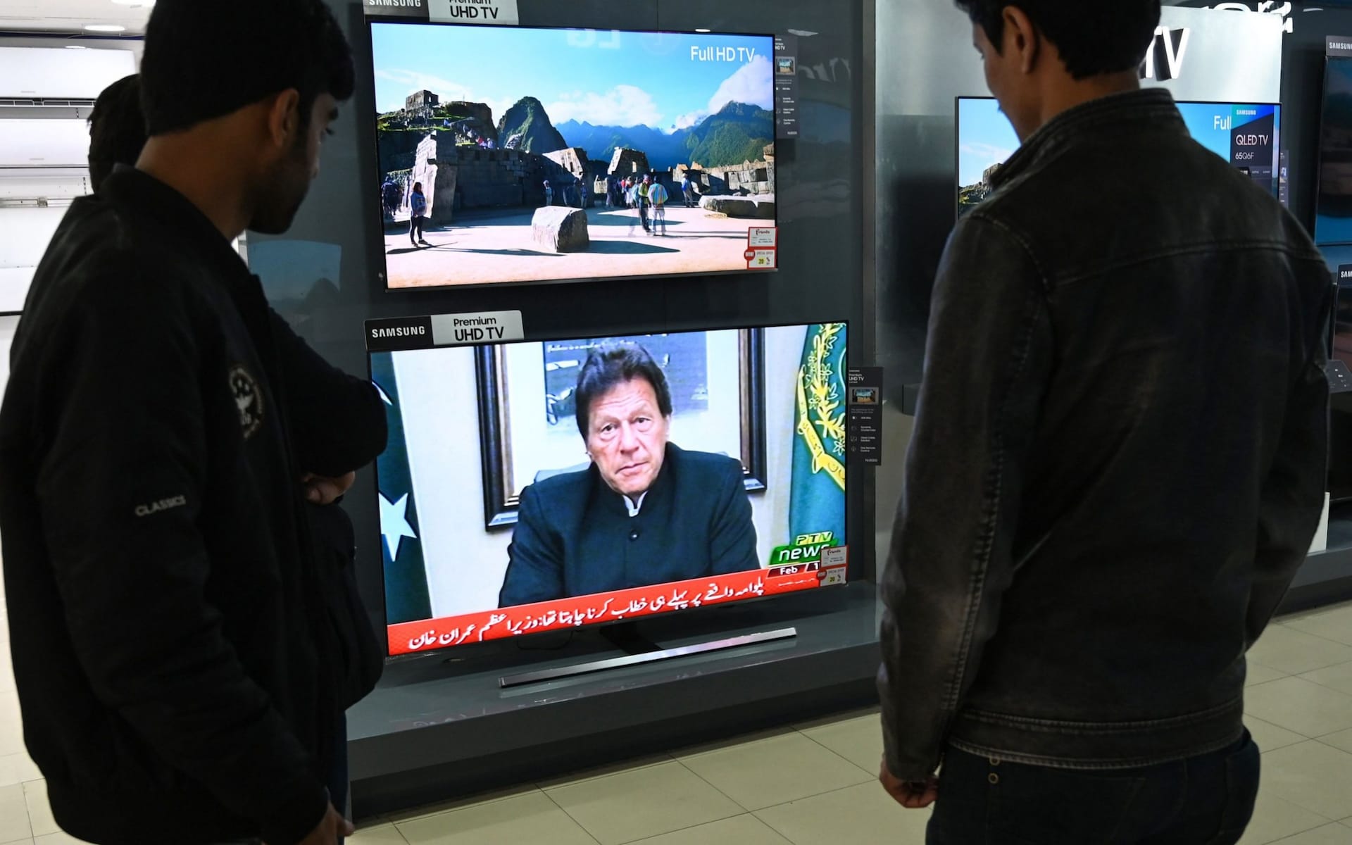 In this file photo people watch Pakistani Prime Minister Imran Khan address the nation on TV following the Feb. 14 suicide bombing in Indian-administered Kashmir, in Islamabad, Feb. 19, 2019.