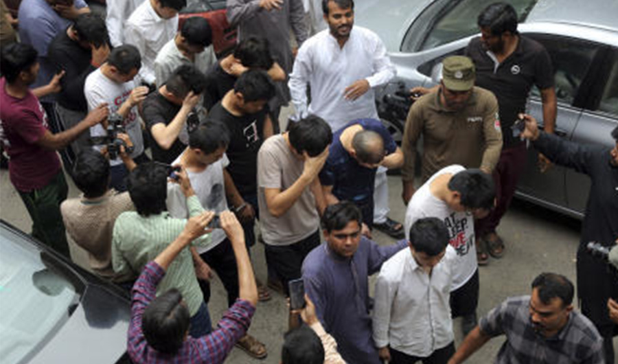 Detained Chinese nationals whose alleged involvement in a trafficking gang to lure Pakistani women into fake marriages, try to shield their faces while they are escorted by Pakistan's Federal Investigation Agency officers to court in Lahore, Pakistan. Pakistan's Federal Investigation Agency arrested the Chinese nationals in raids in the Punjab province in connection with trafficking. The raids followed an undercover operation that included attending an arranged marriage, local media reported. (AP Photo/K.M. Chaudary, File)