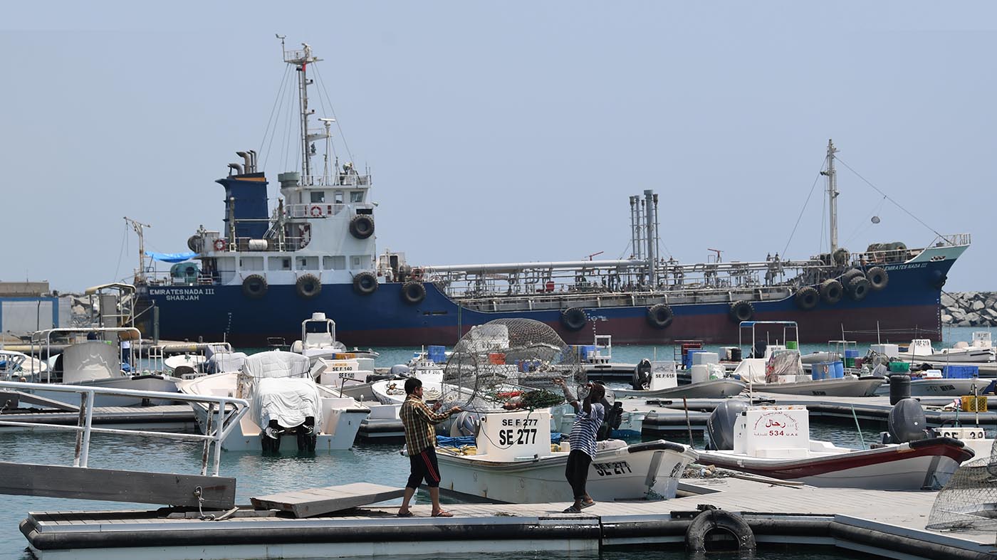 Fishermen check their net in front of ships docked in the port of Fujairah in the east of the United Arab Emirates (UAE) on July 2, 2019. (AFP)