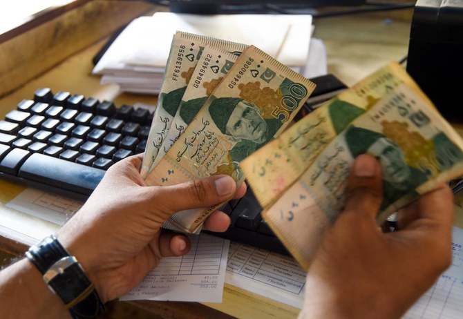 A Pakistani man counts Pakistan’s rupees at his shop in Karachi on May 16, 2019. (AFP)