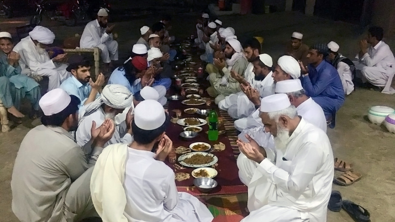 Ewaz Muhammad Khan (first from right) prays along with other villagers after attending a dinner hosted in the honor of his going on Hajj this year. Photo taken on June 26, 2019. (AN Photo)