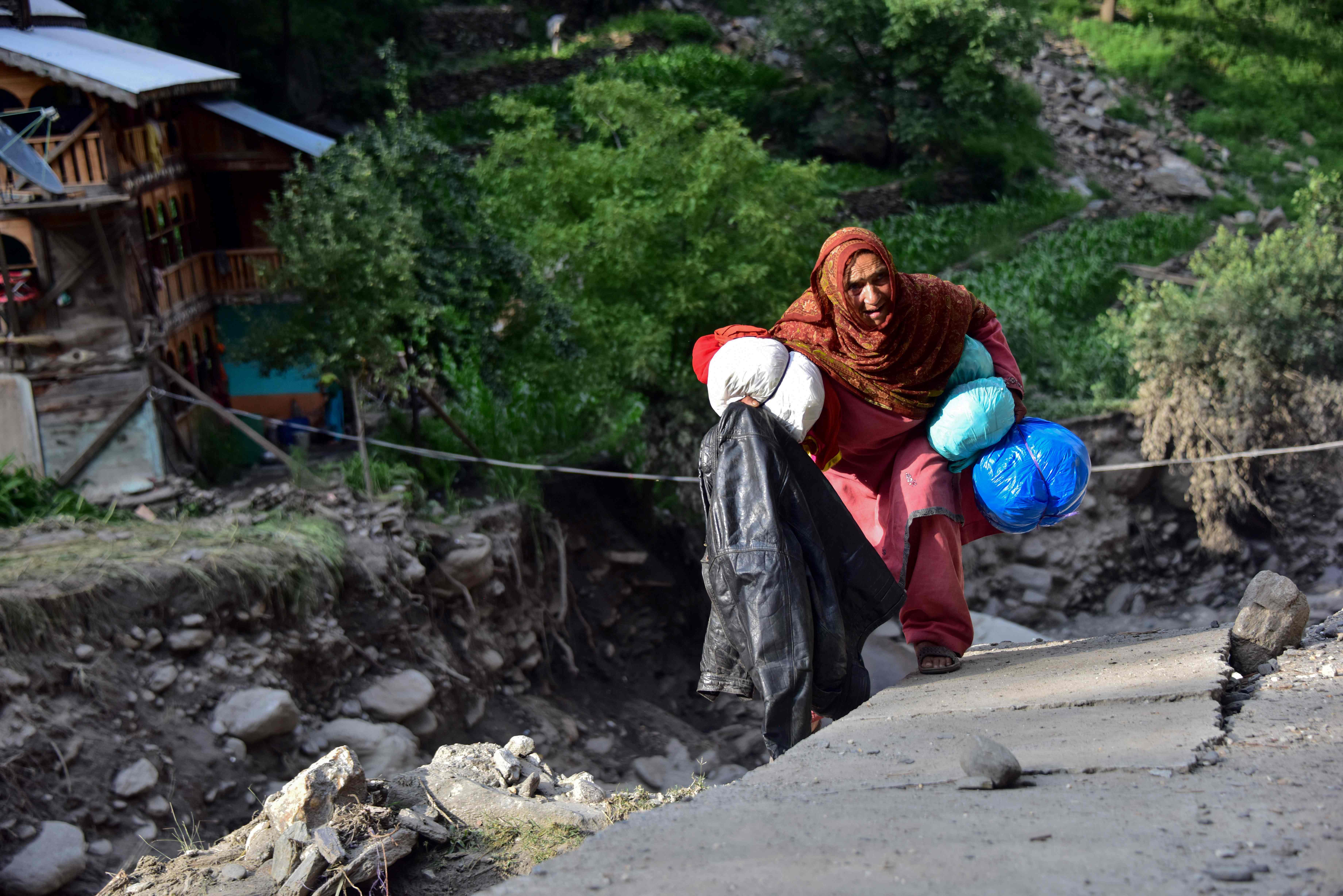 In this picture taken on July 17, 2019, a Pakistani Kashmiri flood-affected victim holds her belongings near her damaged house in Laswa Valley, near the Line of Control in Pakistan-administered Kashmir. (AFP)