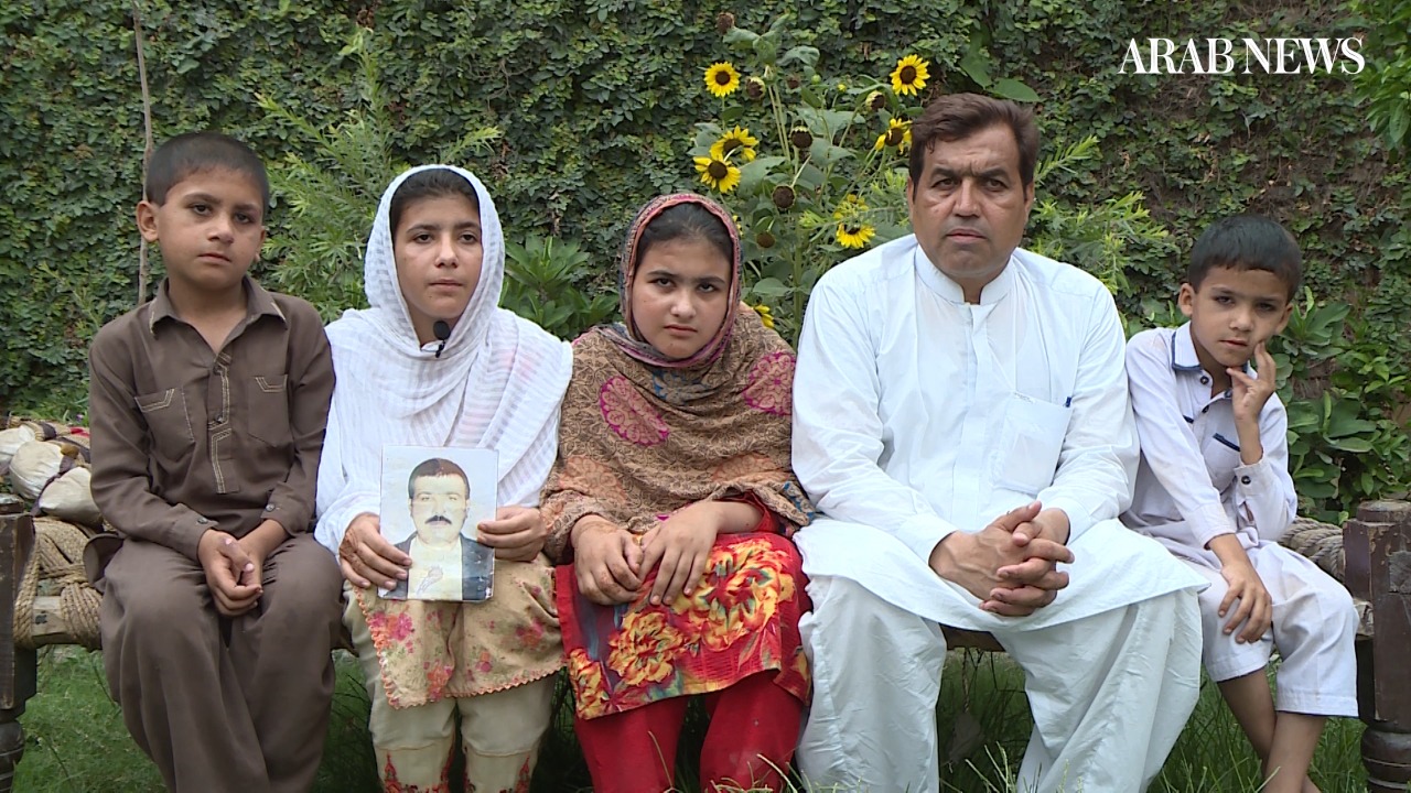 Hidayatullah, the brother of Pkaistani trucker Zahir Hussain Zar Khan, detained in Saudi Arabia since 2012, poses for a photo with Khan's four children in Peshawar, Pakistan. One of Khan's daughters is seen holding a photograph of her father who is set to return to Pakistan after being pardoned by the Kingdom this month. (Photo Arab News)