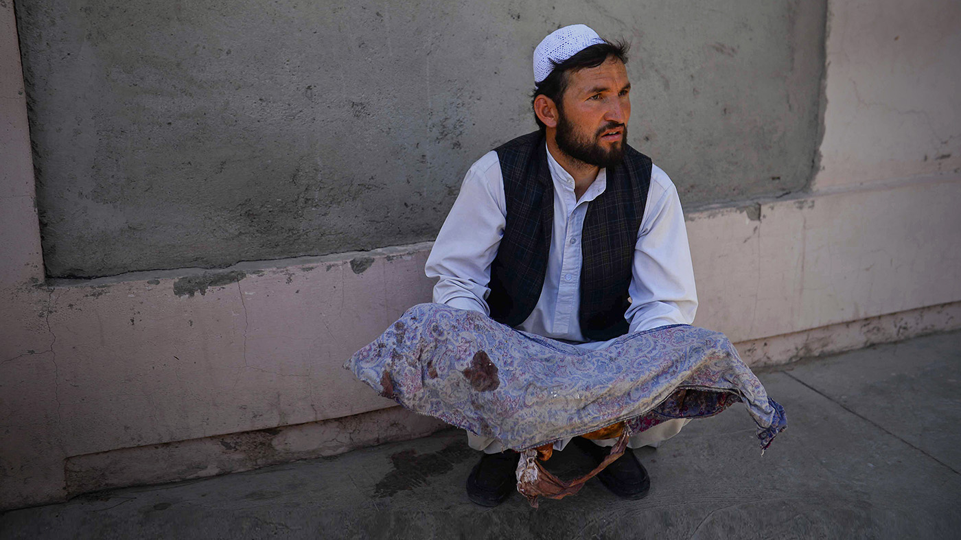 An Afghan man holds the dead body of a child killed when a bus hit a roadside bomb on the Kandahar-Herat highway, at a hospital in Herat on July 31, 2019. (AFP)