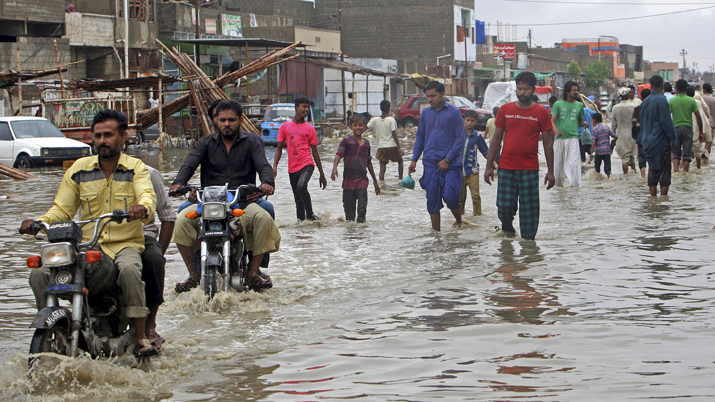 People wade through a flooded street after a heavy rainfall in Karachi, Pakistan, Tuesday, July 30, 2019. (AP)